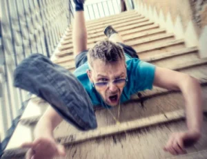 Ein junger Mann fällt kopfüber eine Treppe runter.