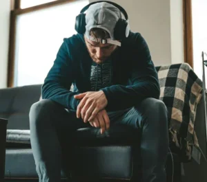 Mann sitzt auf einer Treppe und scheint traurig zu sein. Er hat Kopfhörer auf.