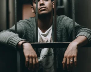 Junger Mann sitzt hinter Gittern.