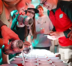 Einige junge Menschen schütten Alkohol in rote Becher.