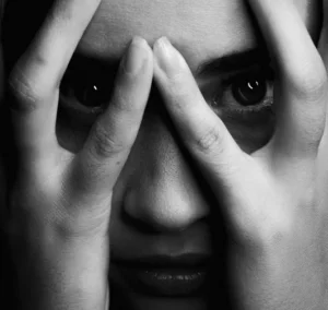 Schwarzweißfoto einer Frau, die sich die Hände vor ihr Gesicht hält.