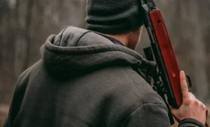 Ein Jäger wird gezeigt, der sein Gewehr an der Schulter trägt.