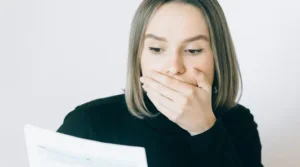 Eine Frau hält sich erschrocken die Hand vor den Mund.