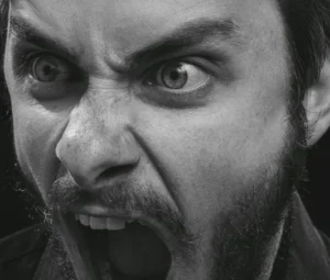 Ein Mann in schwarzweiß schreit wütend in die Kamera.